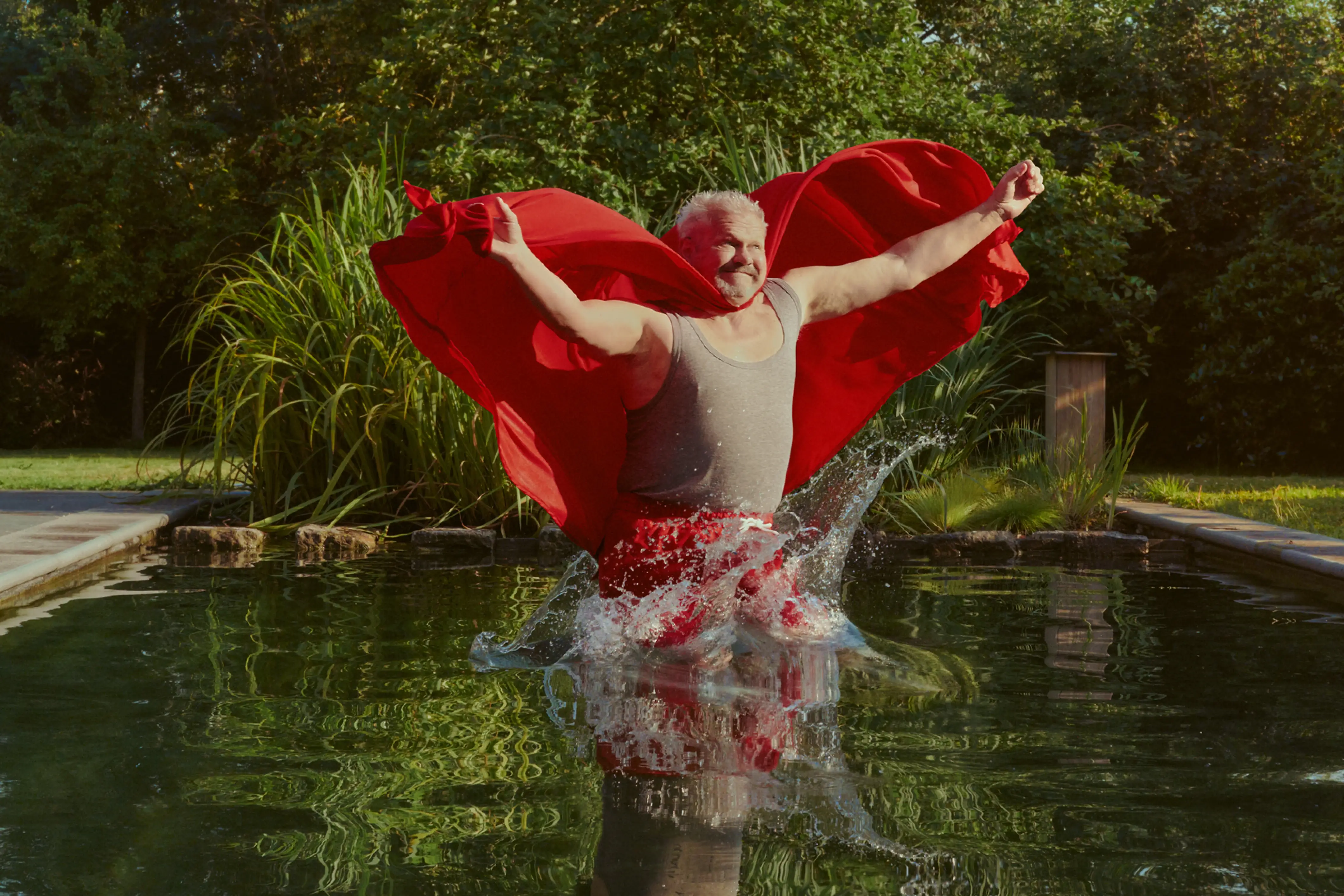 Man in superheldencape in zwembad