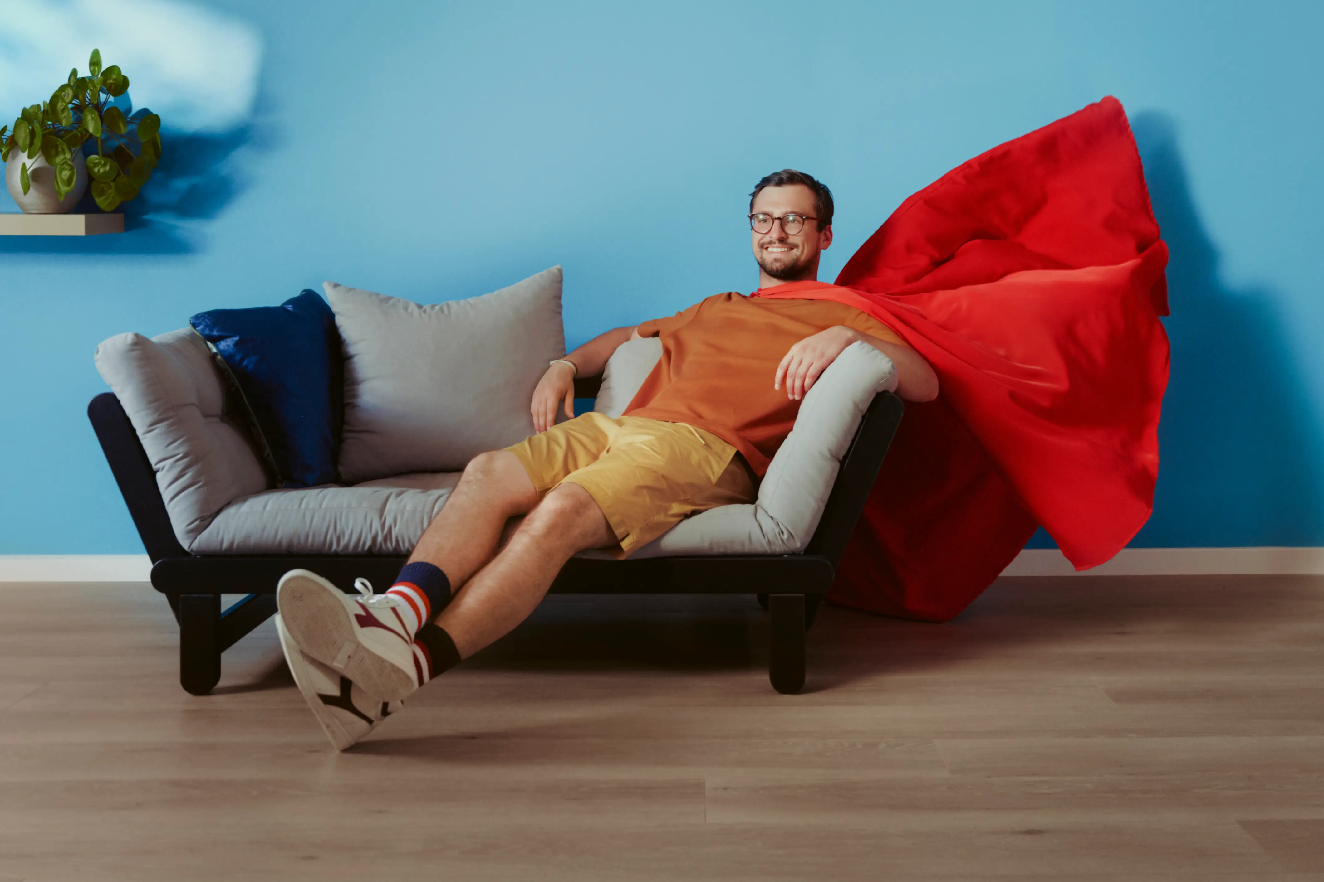 Man in superheldencape op sofa