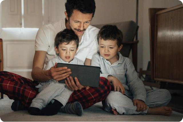 een vader en zijn zoons in hun slaapkamer voor een tabletcomputer 